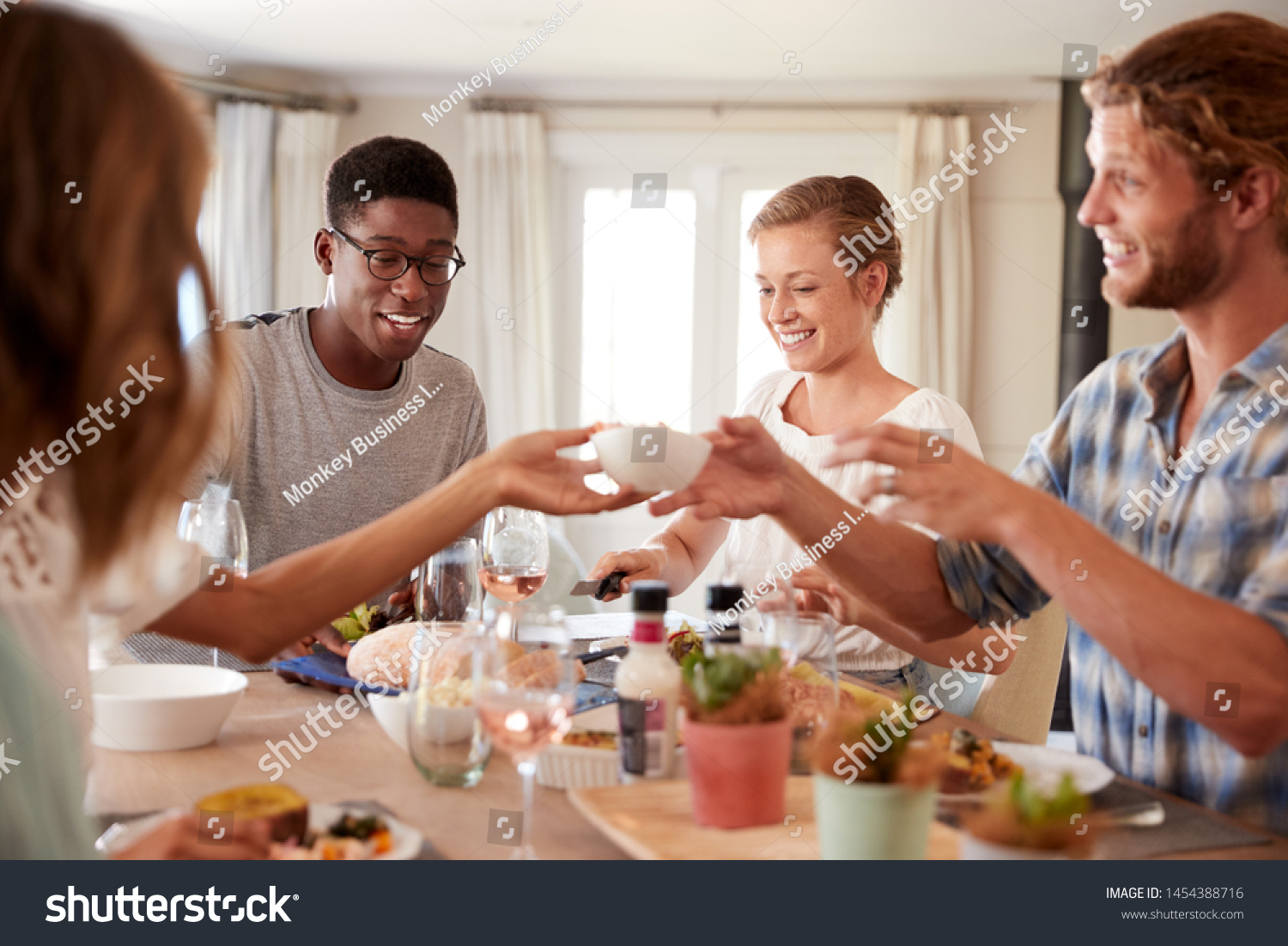 Young adult friends passing a dish across the dinner table at lunch, close up #1454388716