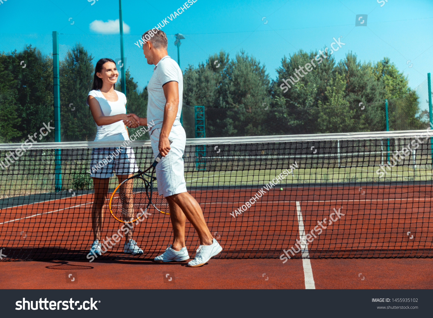 Beaming wife. Beaming wife wearing white t-shirt feeling happy after playing tennis with husband #1455935102