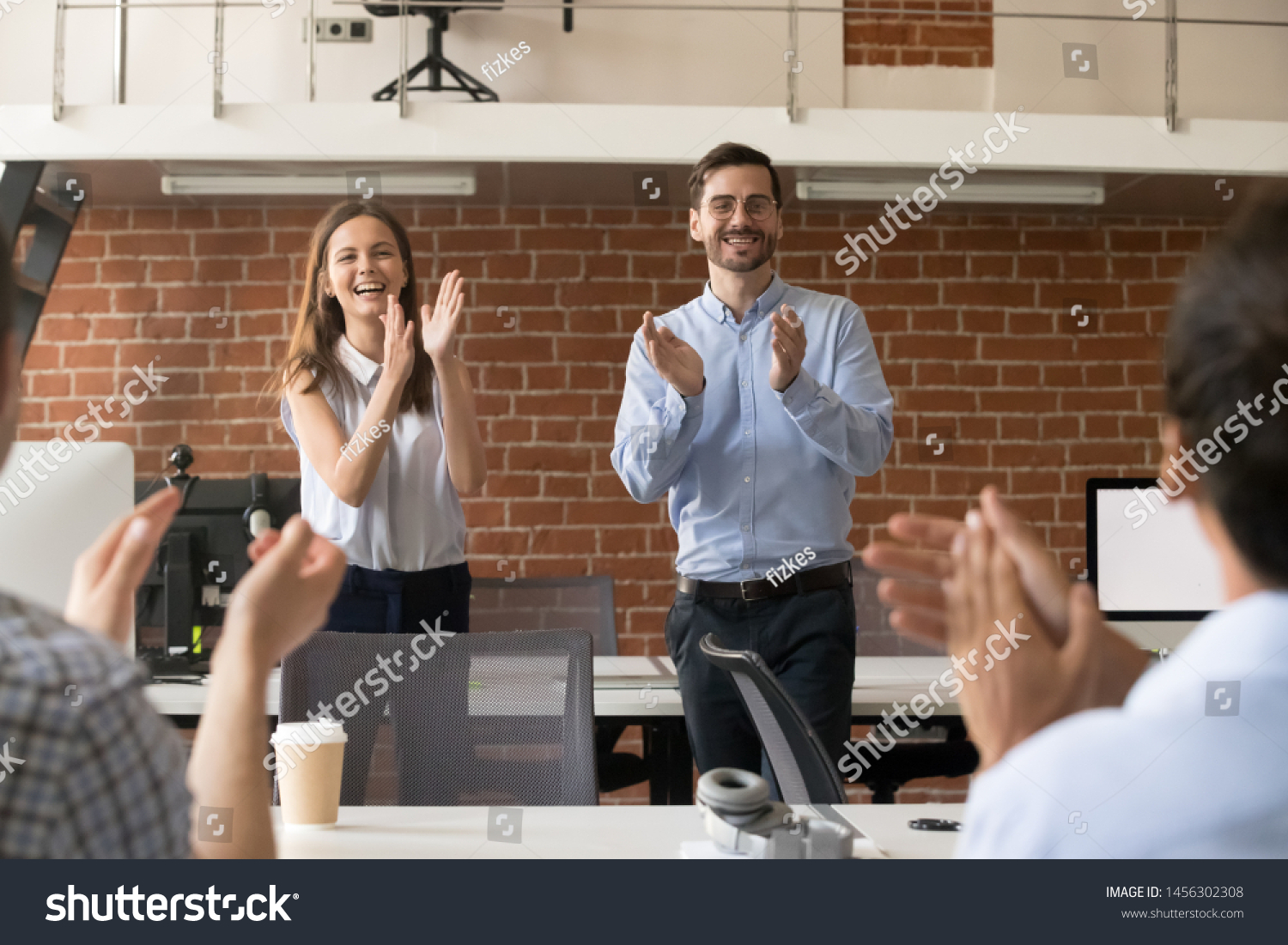 Excited company managers stand applauding congratulating team with work success, boss or CEO clap greeting coworker with promotion or goal achievement, supporting colleague. Reward concept #1456302308