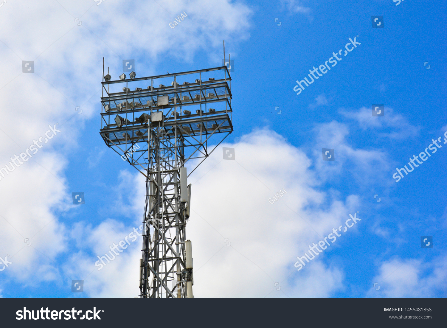Lighting support. Stadium Post Lighting. Tall pillar with spotlights to illuminate a football stadium against the sky with clouds #1456481858