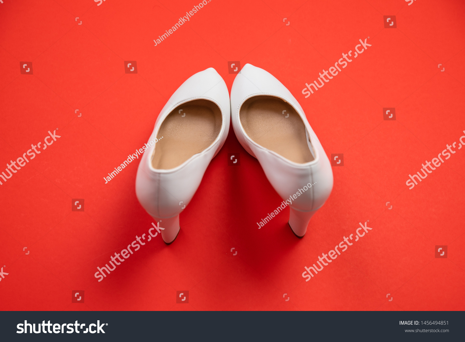 White high heeled shoes on red background - top view concept - blank empty room space for text or copy. Suitable for holidays like Valentine's or Christmas. Classic dress up fashion. Heels pigeon toed #1456494851