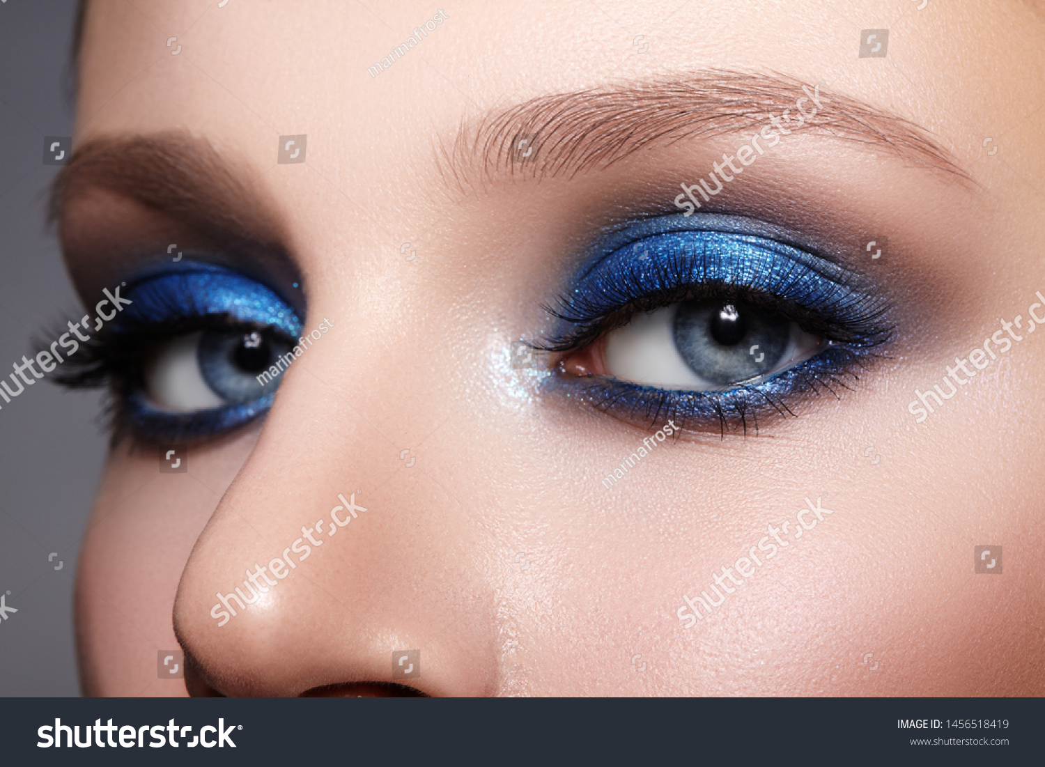 Closeup Macro of Woman Face with Blue Eyes Make-up. Fashion Celebrate Makeup, Glowy Clean Skin, perfect Shapes of Brows. Shiny Simmer and Rouge #1456518419