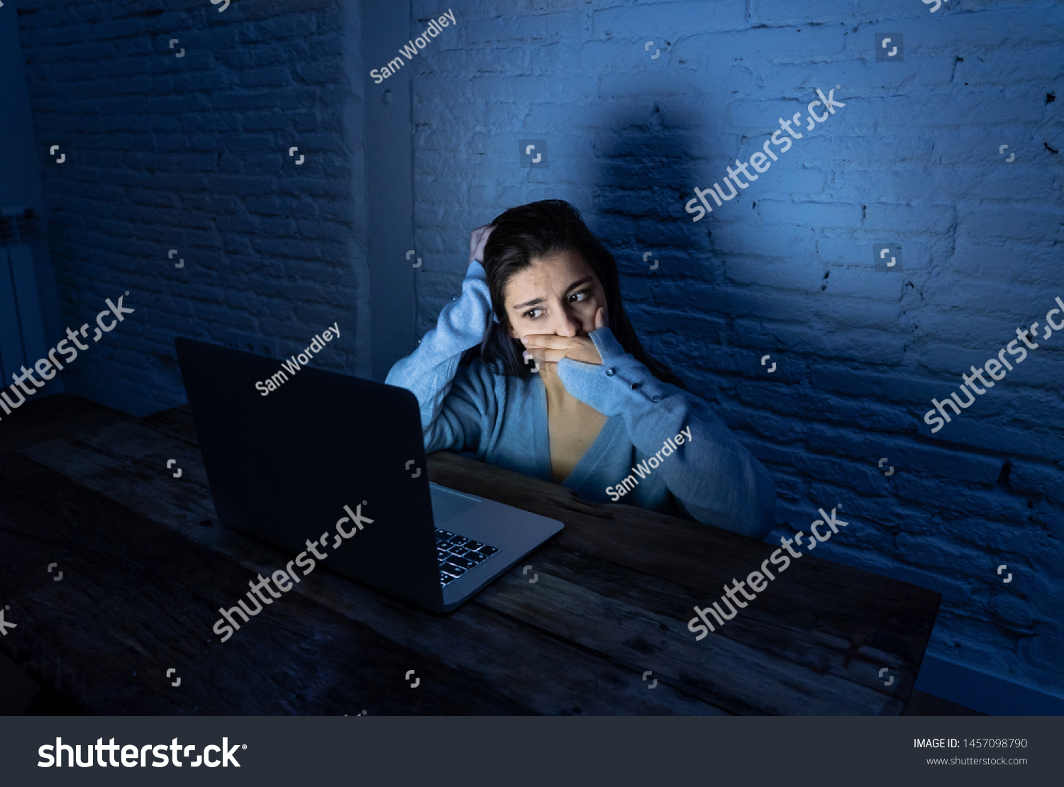 Dramatic portrait of sad scared young woman stressed and worried staring at laptop suffering cyber bullying and harassment. Victim of online abuse and intimidation by stalker. In dangers of internet. #1457098790