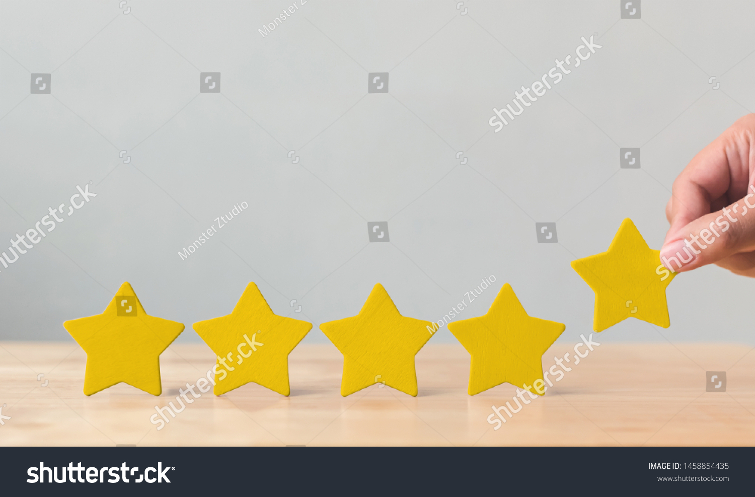 Hand putting wooden five star shape on table. The best excellent business services rating customer experience concept #1458854435