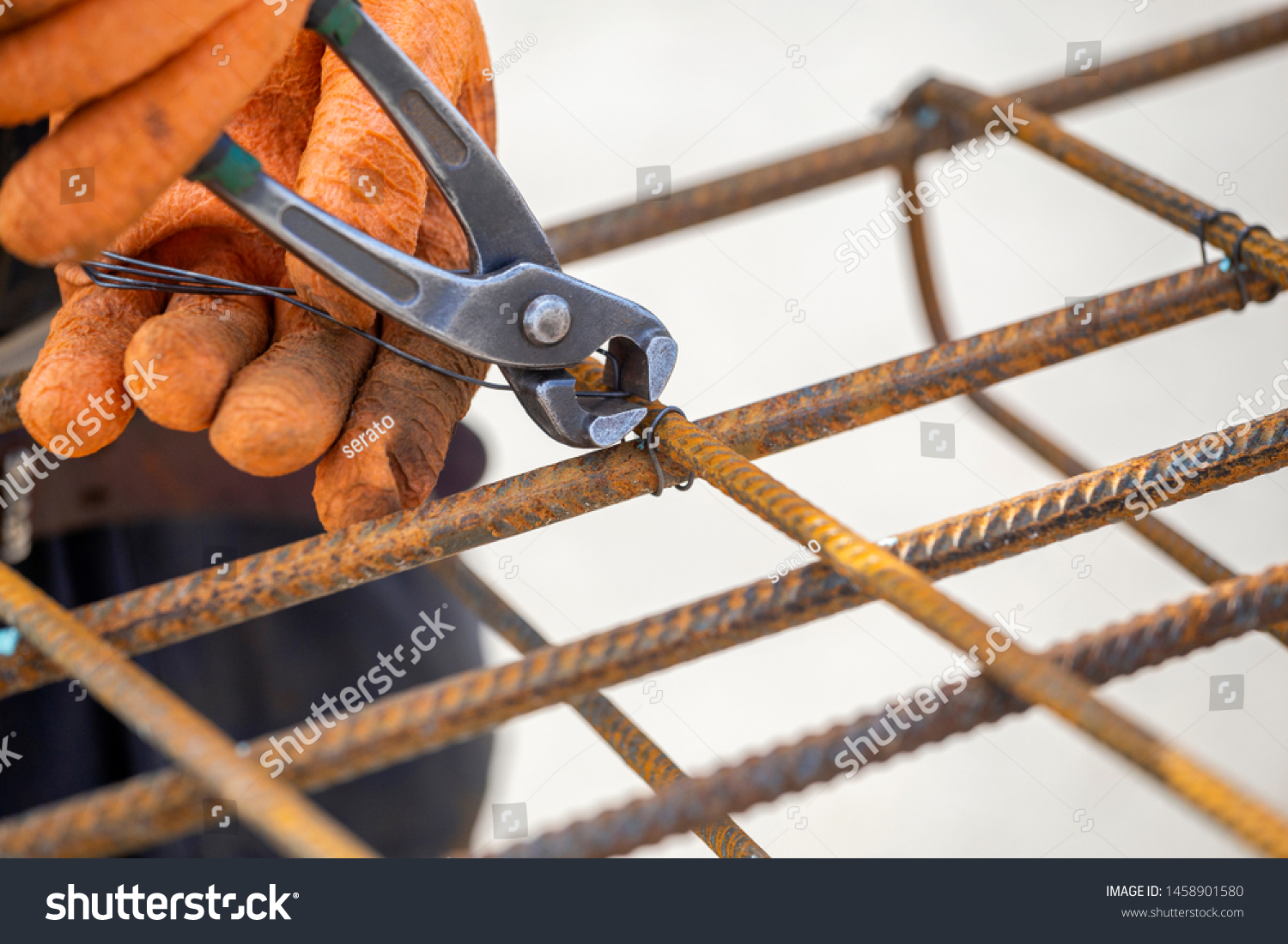 Tying reinforcing steel bars (rebar) for the construction. Tightening wire using a pincers. #1458901580