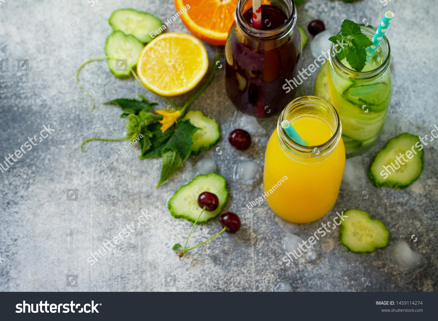 Various refreshments drinks - detox cucumber water, cherry juice and orange juice on stone table. Top view flat lay with copy space for your text. #1459114274