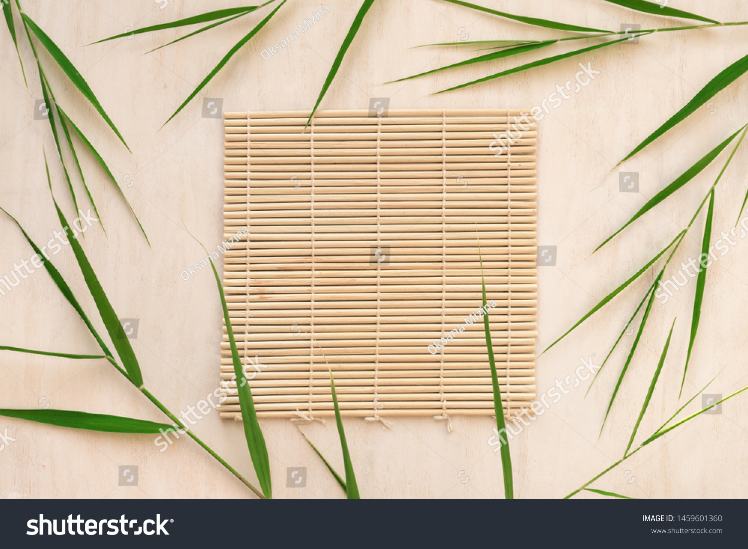 Green bamboo leaves and bamboo mat, asian style background, top view, copy space. Trendy bamboo leaves flat lay on white wooden background. #1459601360