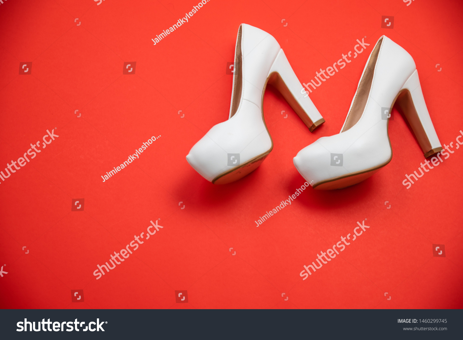 White high heeled shoes on red background - top view concept - blank empty room space for text or copy. Suitable for holidays like Valentine's or Christmas. Classic fashion. Heels walking left #1460299745