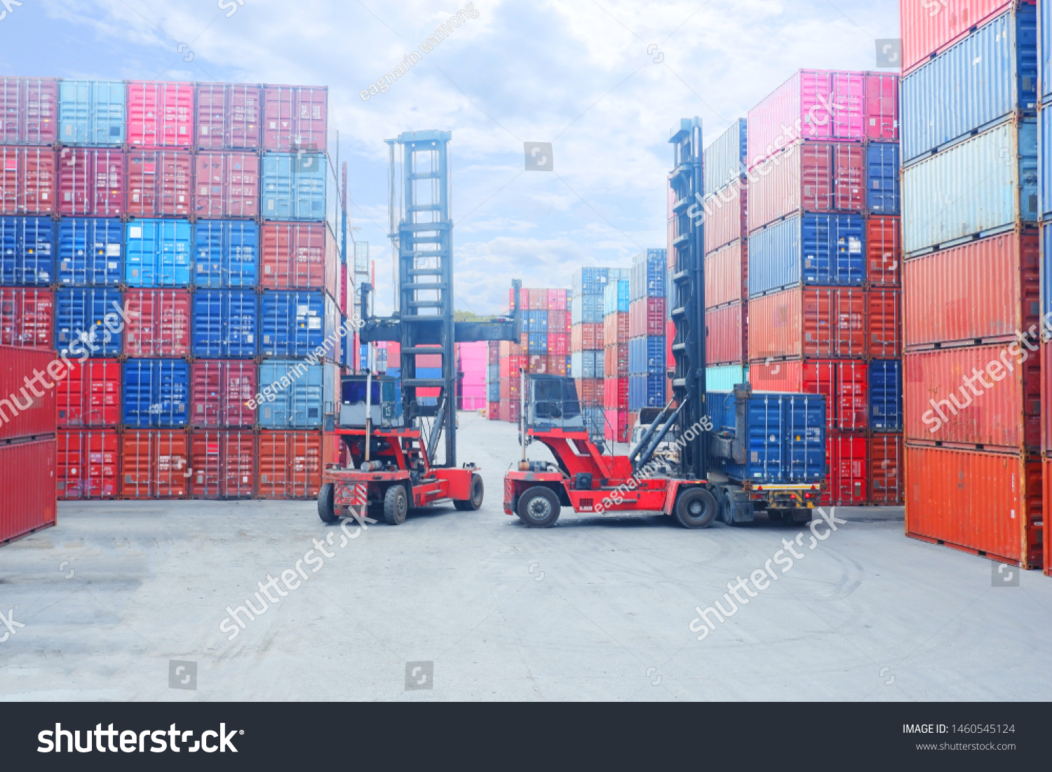 Forklift truck lifting cargo container in shipping yard or dock yard against sunrise sky with cargo container stack in background for transportation import,export and logistic industrial concept #1460545124
