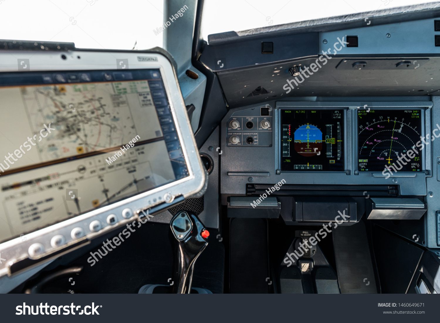 Airplane Cockpit, Captain site with the Primary Flight Display and navigation display in front and the computer with navigational charts just above the side stick  #1460649671