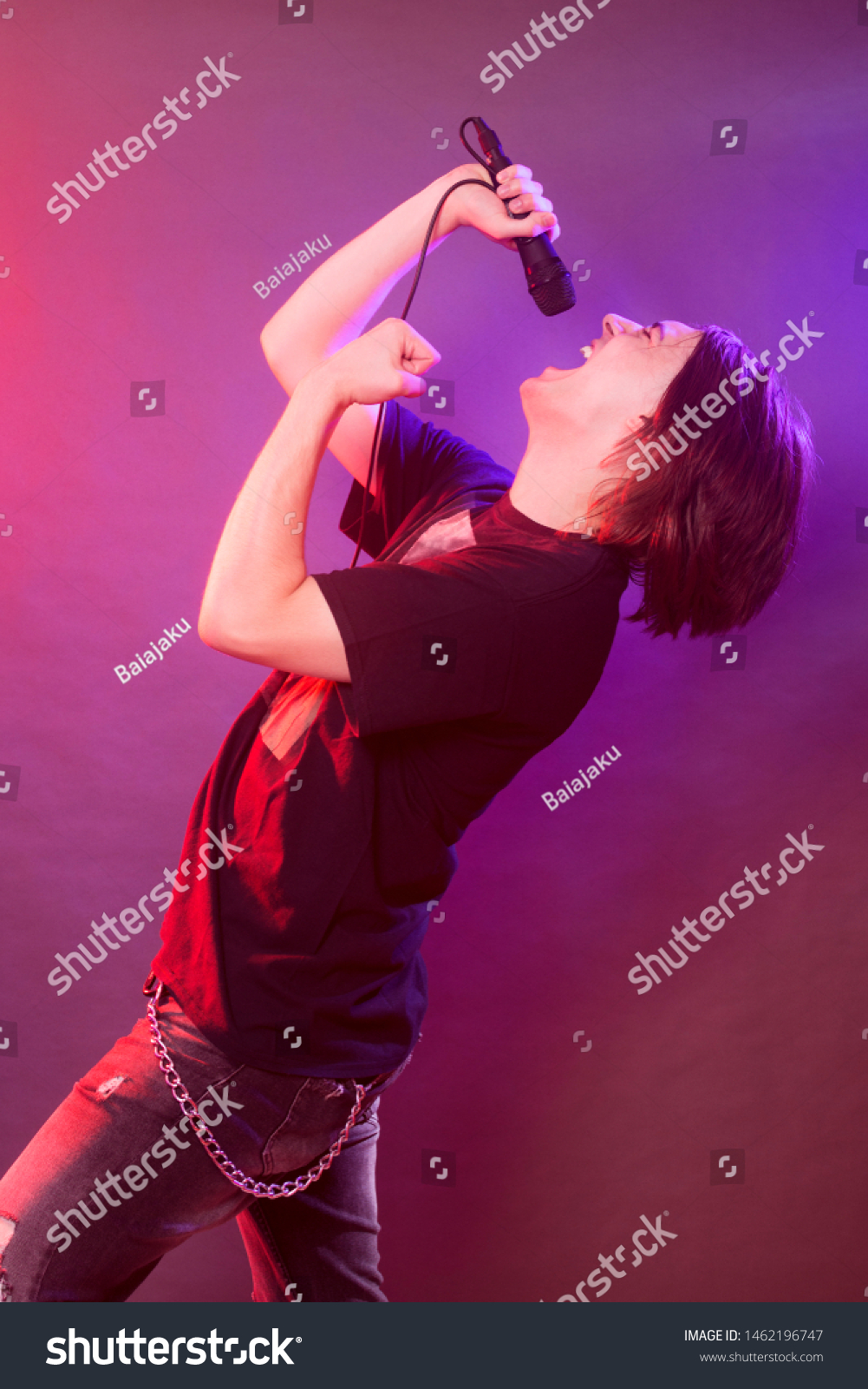 The young guy is singing and screaming in microphone on stage, concert concept. #1462196747