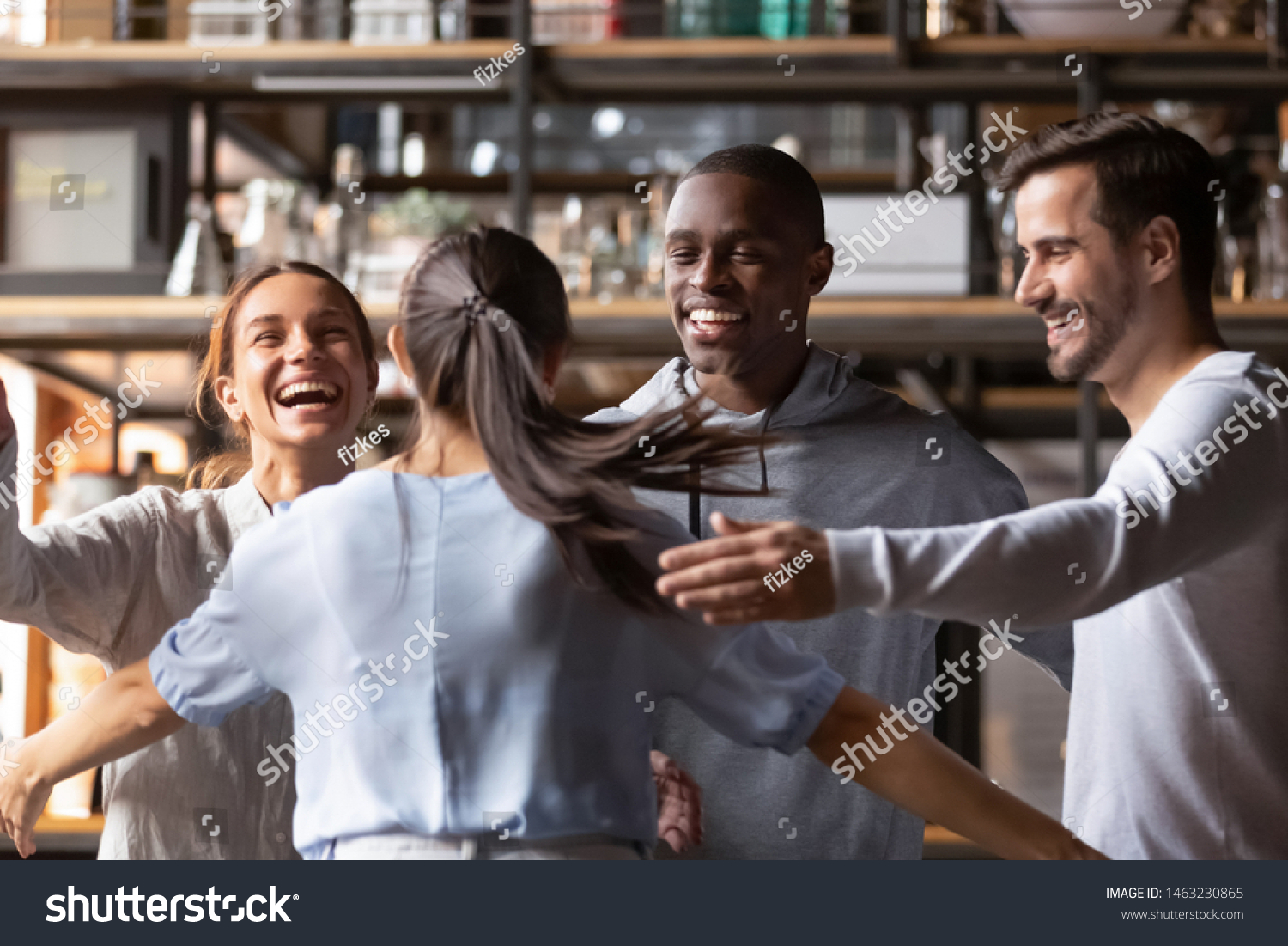 Excited multiracial young people hanging out together in cafe meeting new girlfriend giving hug, happy diverse friends feel overjoyed welcoming colleague relaxing having fun in bar or restaurant #1463230865