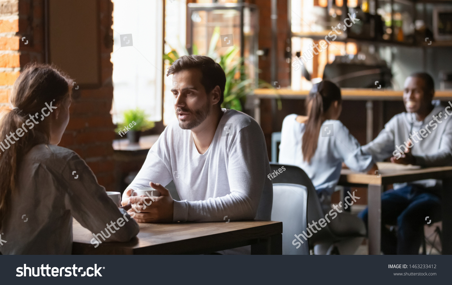 Millennial couple sit at cafe table drinking hot coffee talking discussing things, diverse young men and women meeting in coffeehouse speaking get acquainted taking part in speed dating. Love concept #1463233412