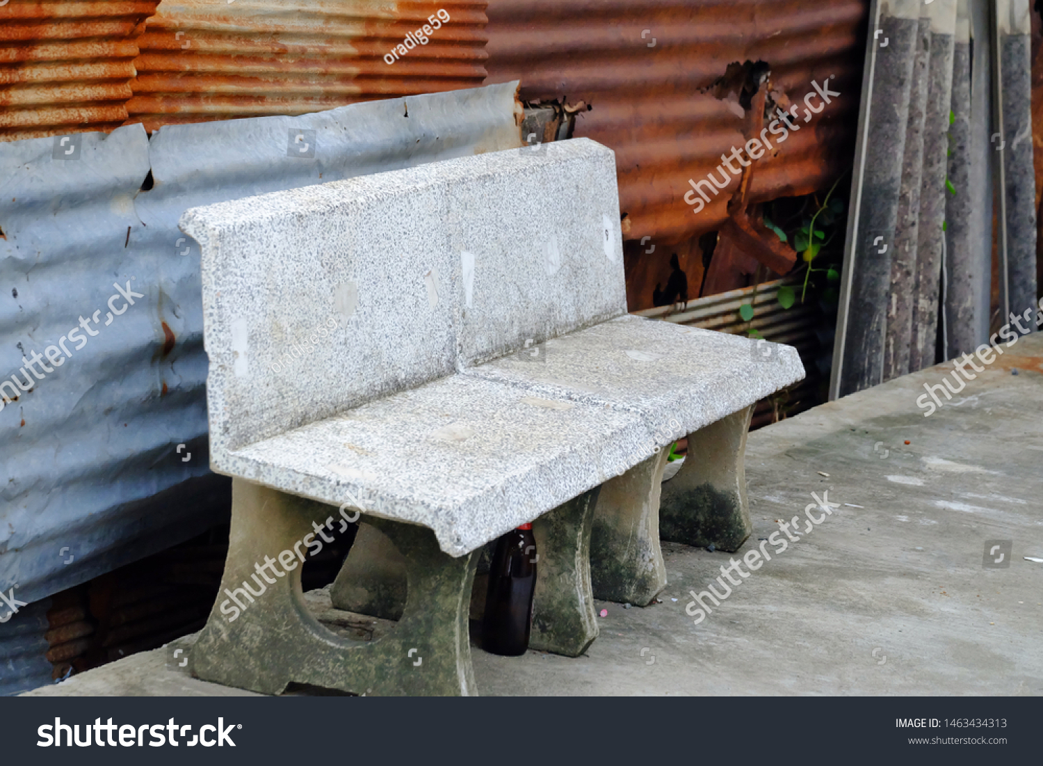 An empty old stone bench on rough ground cement with rusty zinc wall background  #1463434313