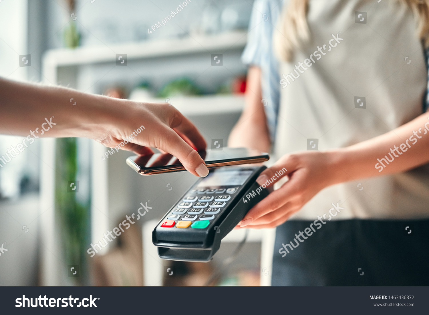 Female florist in flower shop. Young beautiful blonde selling flowers and succulents. Cropped image of customer paying using smart phone. #1463436872