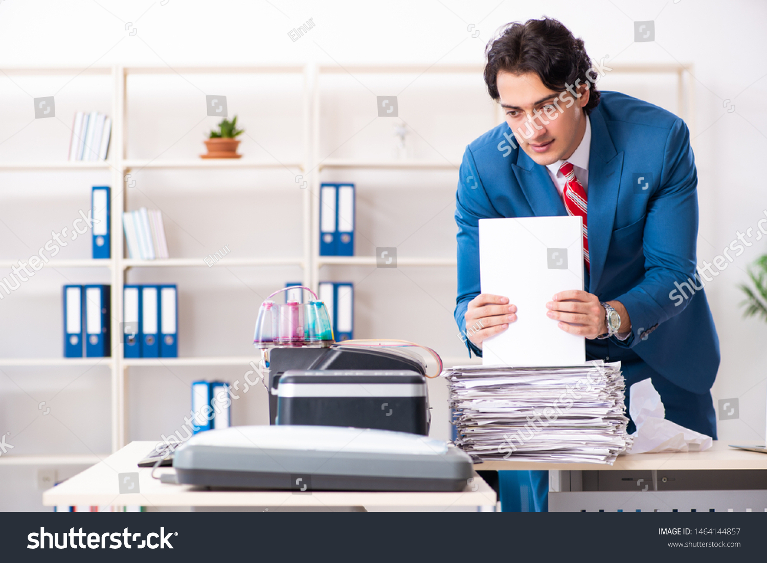 Young employee making copies at copying machine  #1464144857