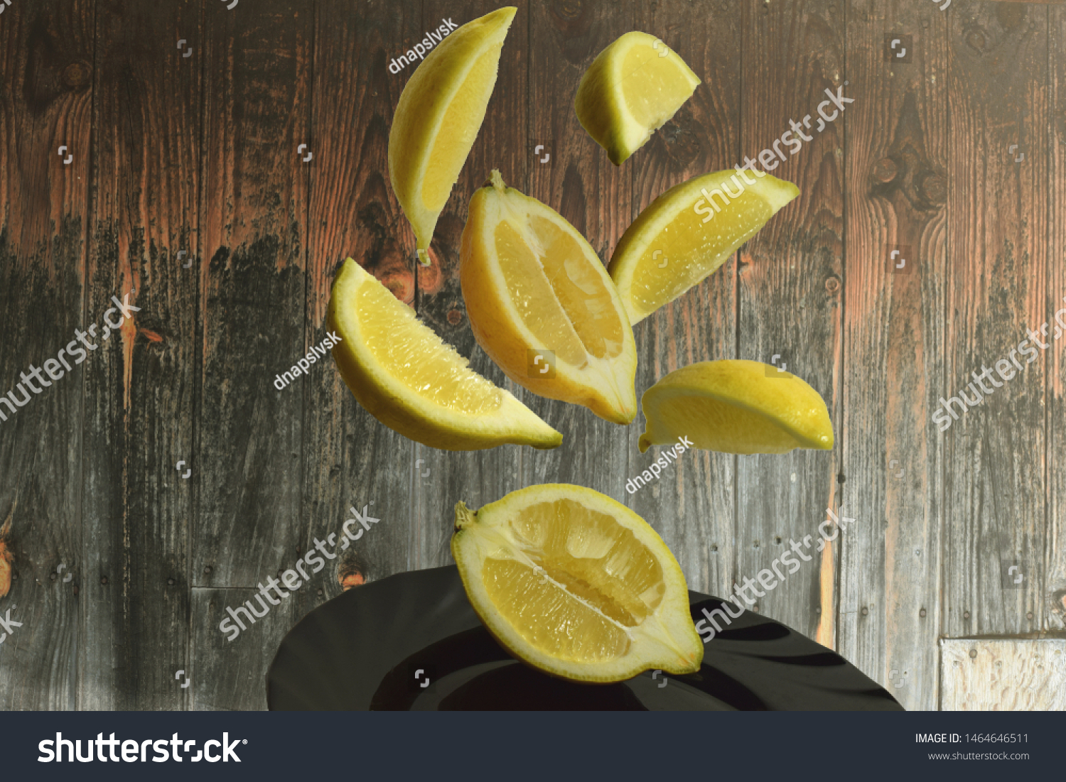  pieces of lemon flying in the air on the black plate with a wooden background #1464646511