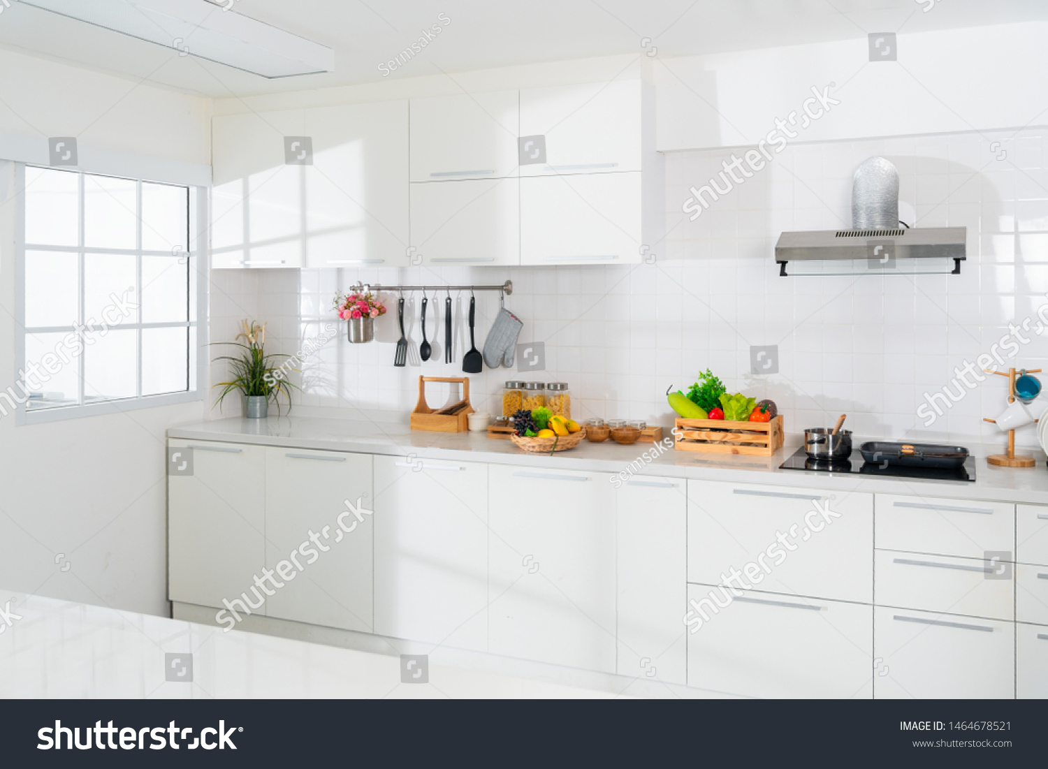 Modern white kitchen with counter and white details, minimalist interior, Full set of kitchen equipment, pan, pot, electric hob, flipper, vegetable, fruit. #1464678521