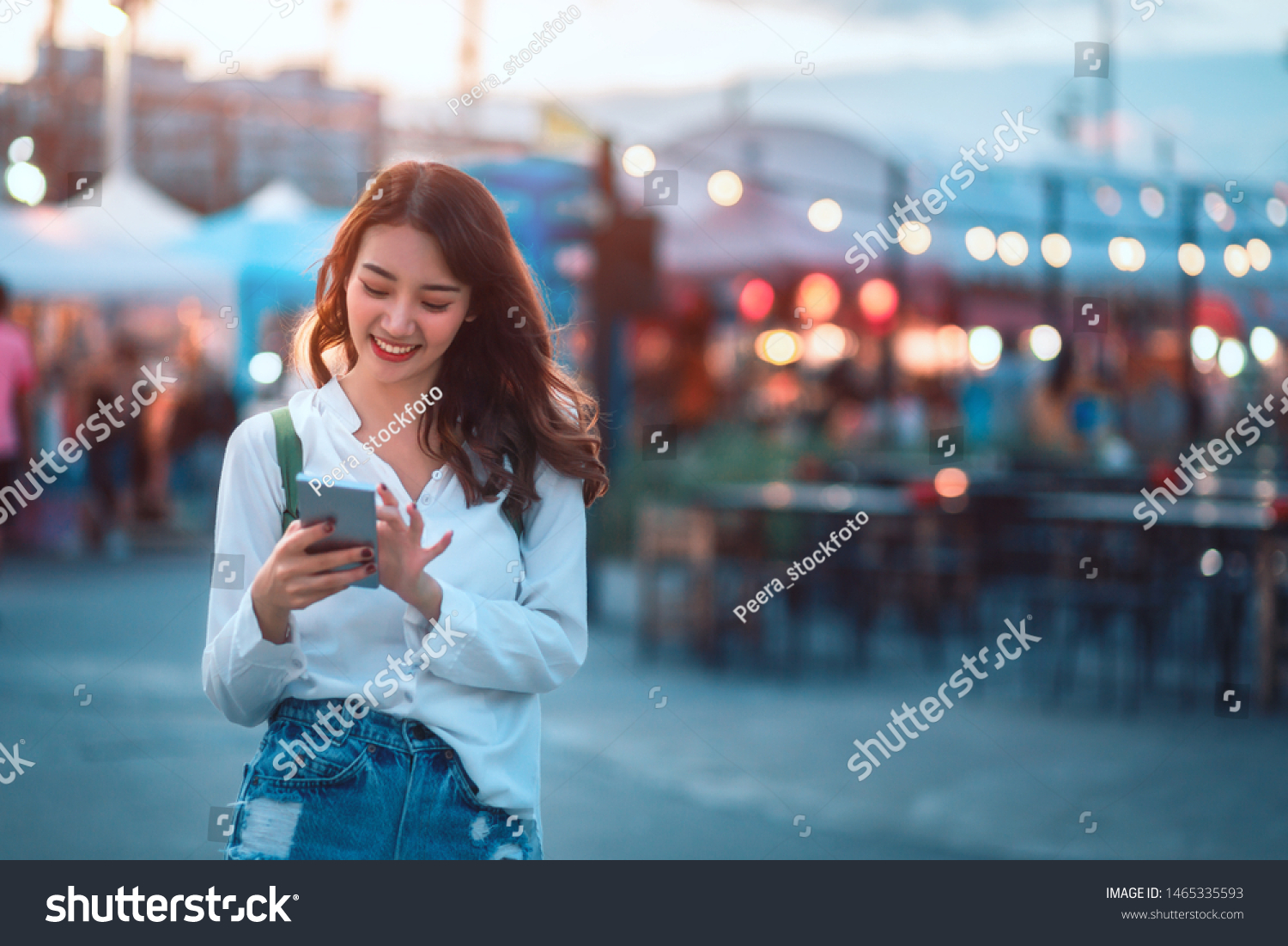 Happy young travel asian woman using mobile phone and relax on street market against light bokeh background at dusk in Bangkok, Thailand, Travel vacation city concept #1465335593