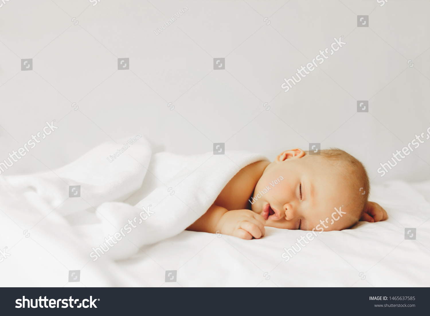 Beautiful baby sleeps on the bed in white sheets. #1465637585