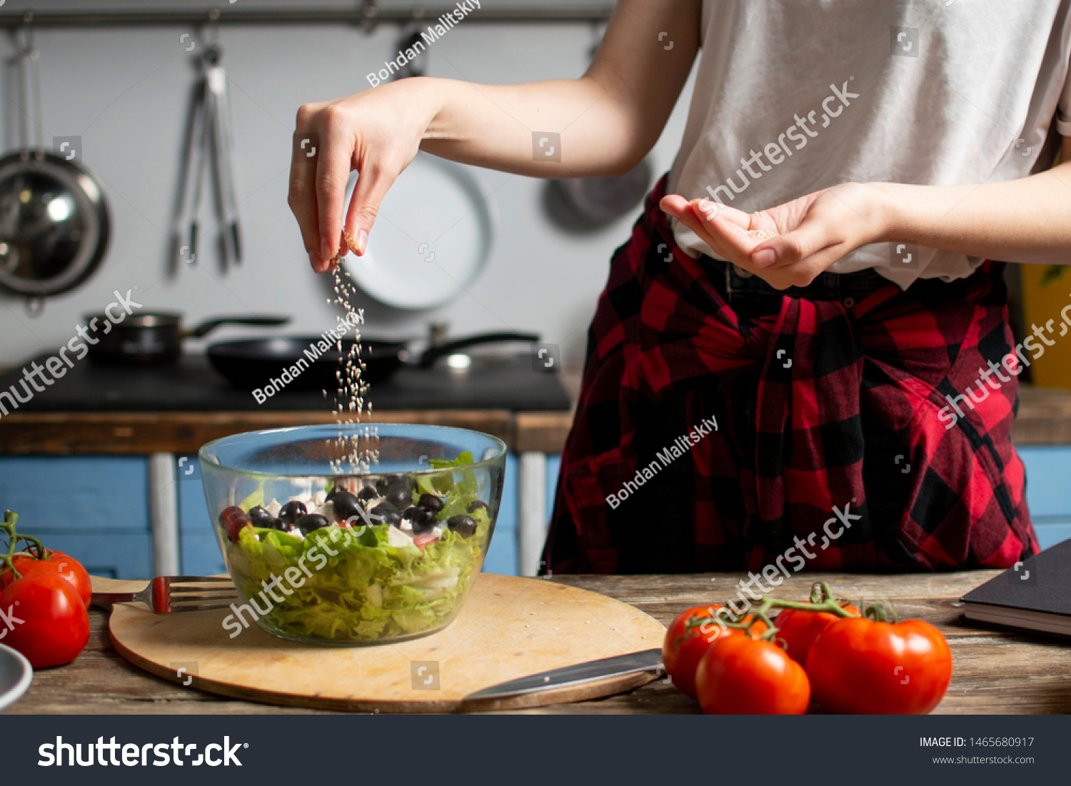 young cheerful girl prepares a vegetarian salad in the kitchen, she salts and adds spices, the process of preparing healthy food #1465680917