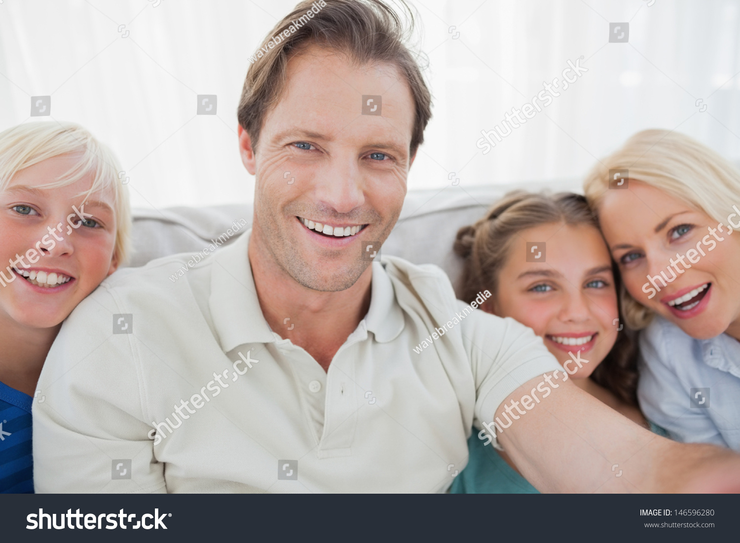 Father taking pictures of his family sitting on the couch #146596280