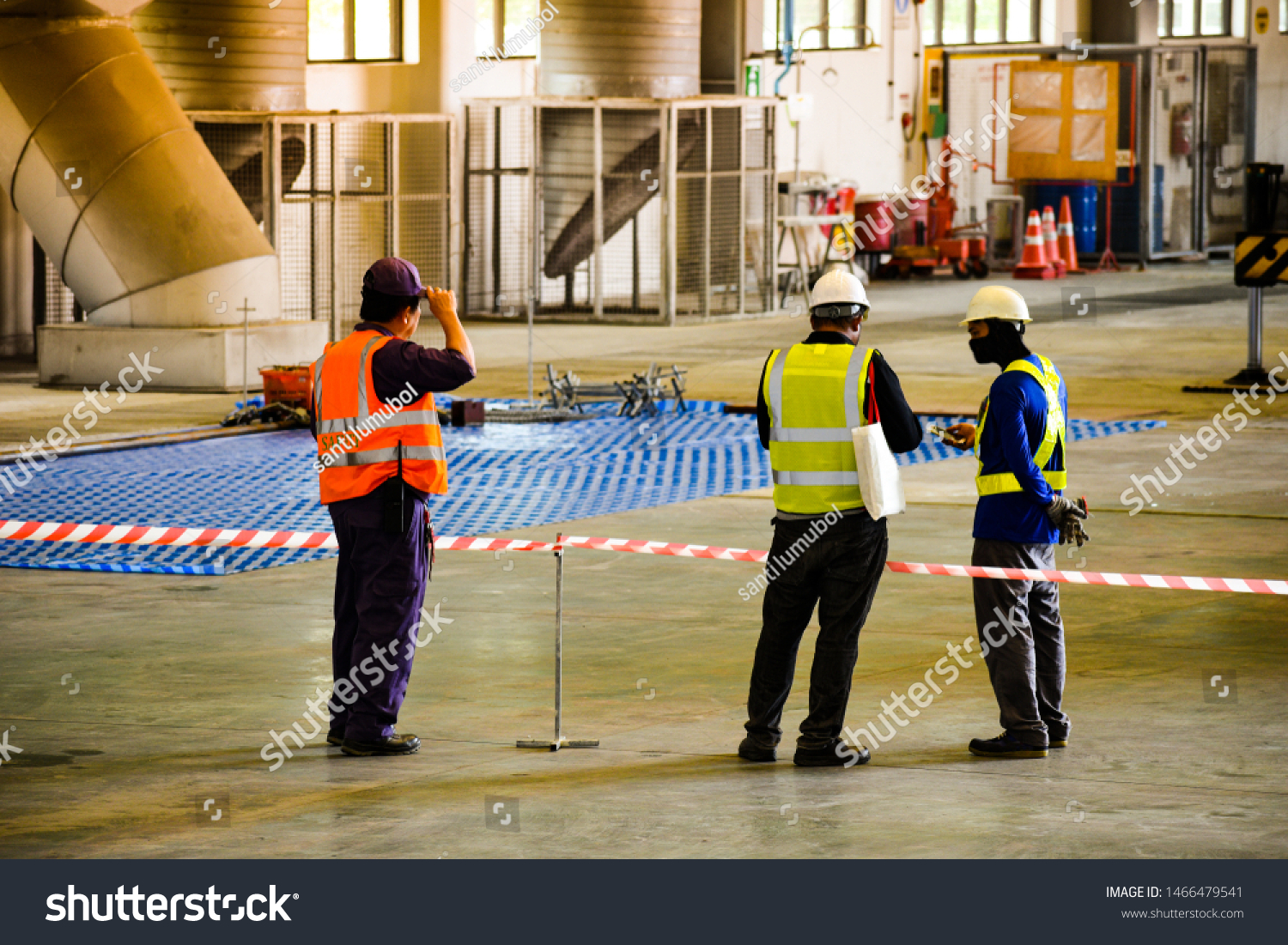 Worker stretching the red white warning tape to the pole at construction site.Red and white Hazardous restricted area tape at construction area of factory to mark territory works. #1466479541