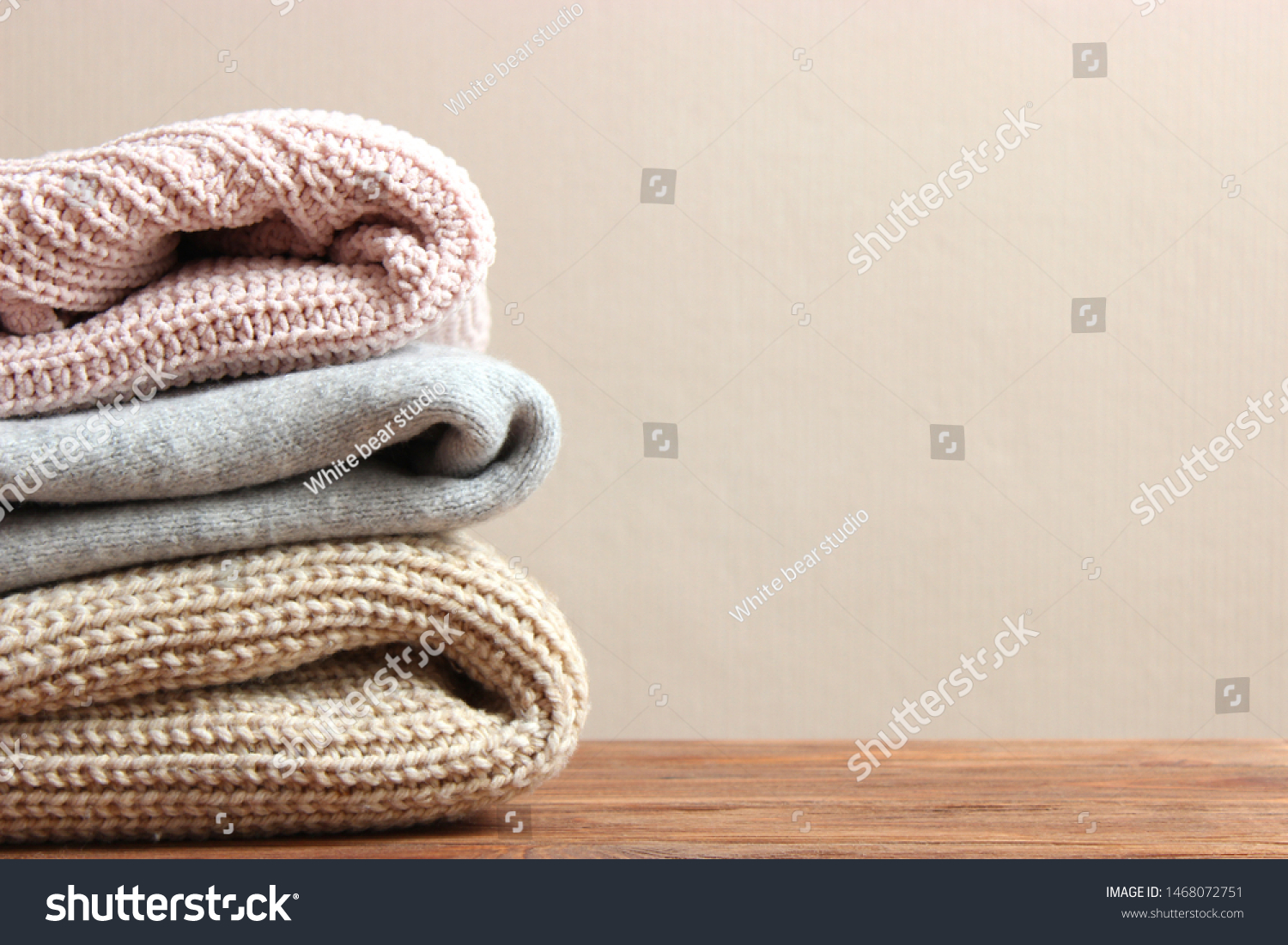 A pile of warm sweaters on a wooden table on a color background. Autumn and winter clothes.
 #1468072751