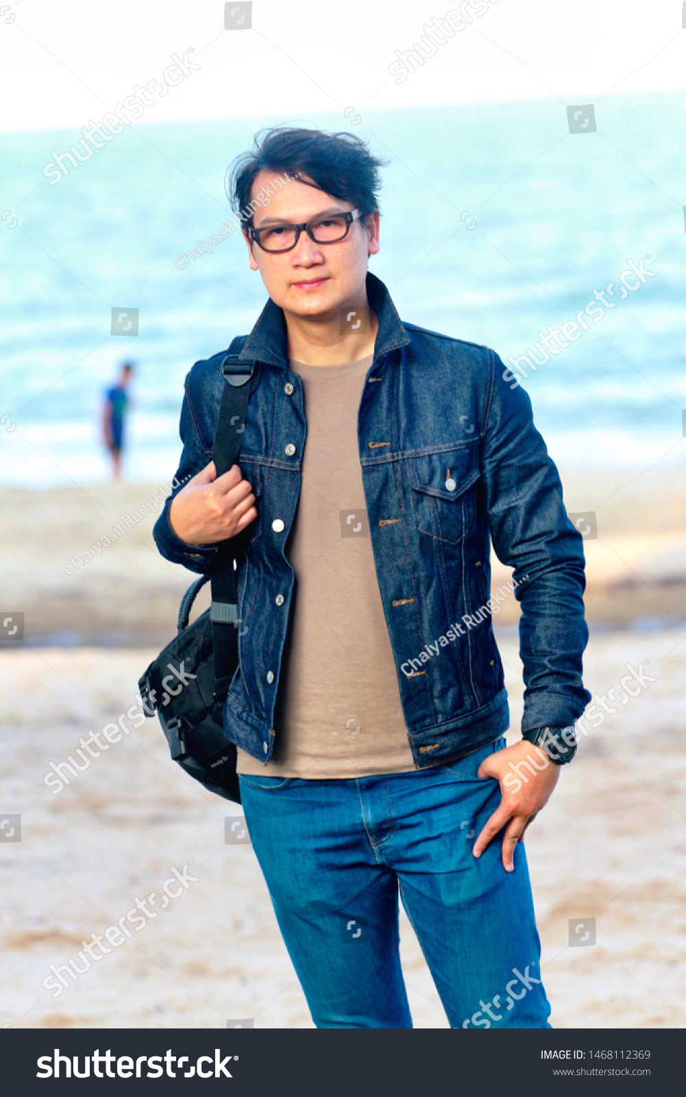 A young man wearing glasses wearing a denim jacket #1468112369