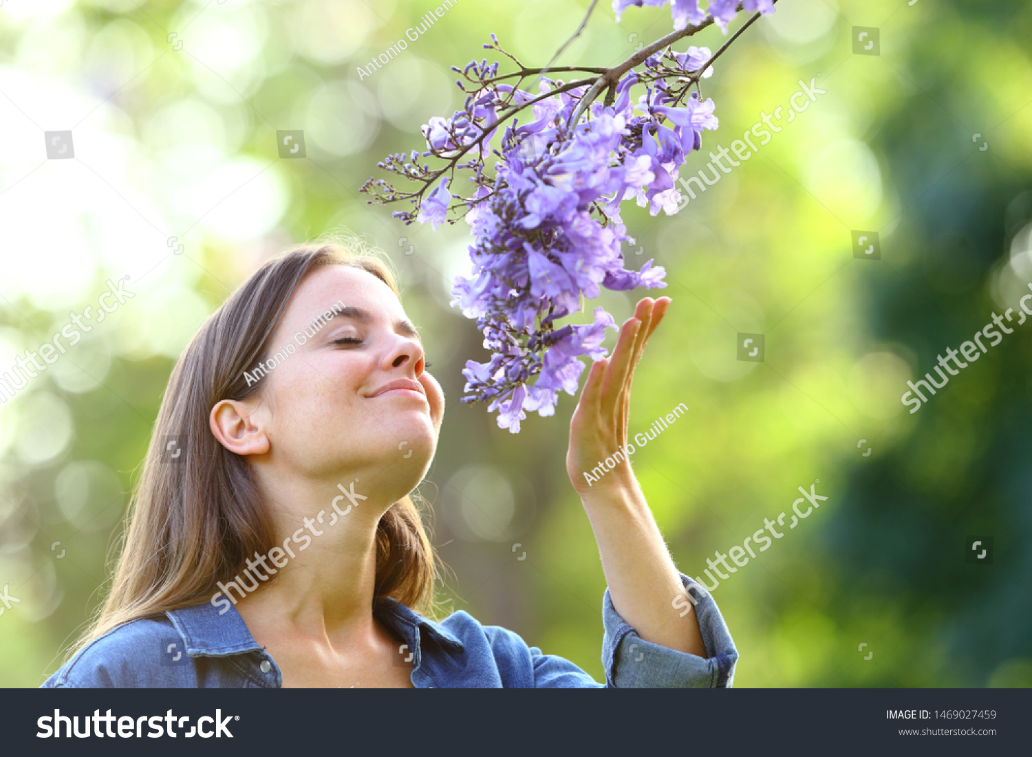 Candid woman smelling flowers standing in a park #1469027459
