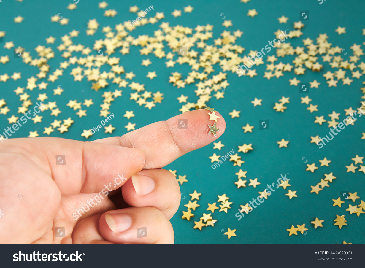 Hand touches solid confetti in the form of stars. The concept of touch, tactility, feelings. #1469629961