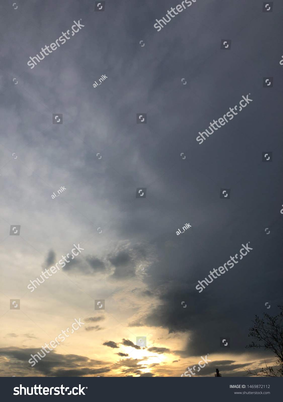 Dense clouds in twilight sky in evening.Image of cloud sky on evening time.Evening sky scene with golden light from the setting sun. Tree silhouette on a cloudy evening sky #1469872112