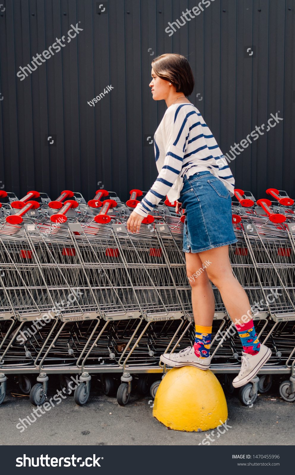Young adult female staying near shopping trolleys. #1470455996