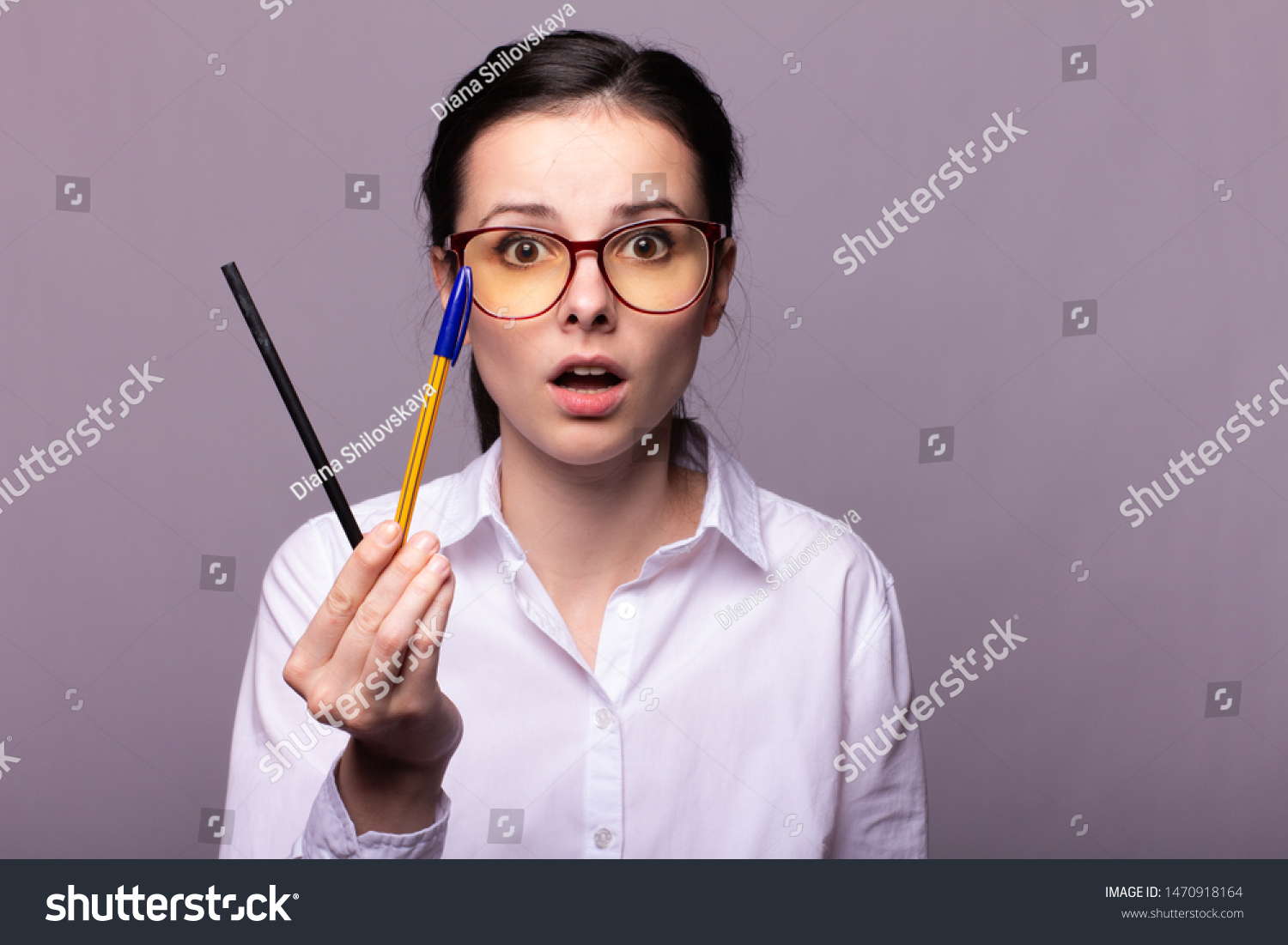 
girl in a white shirt and glasses holds a pencil and a pen in her hand #1470918164