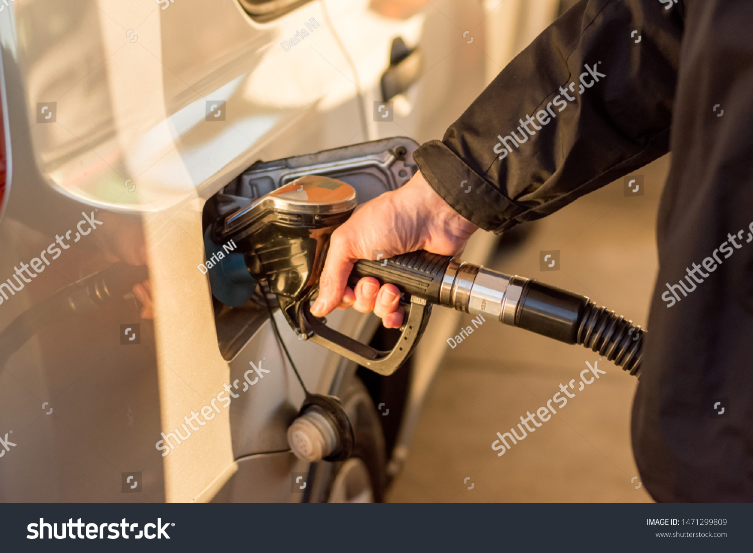 A man hand holding pump filling gasoline. Pumping petrol into the tank. A car refuel on gas station #1471299809