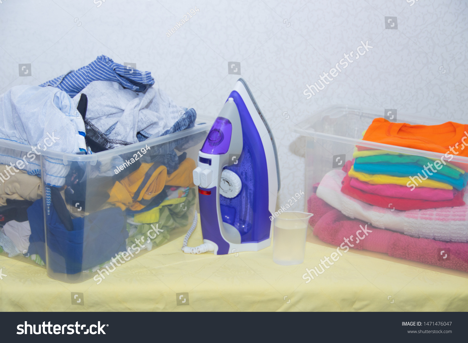 Iron and baby clothes. Colored clothes on an ironing board. Bright t-shirts. Ironed and non-ironed colored children's underwear on the board. Ironing board. A pile of things. #1471476047