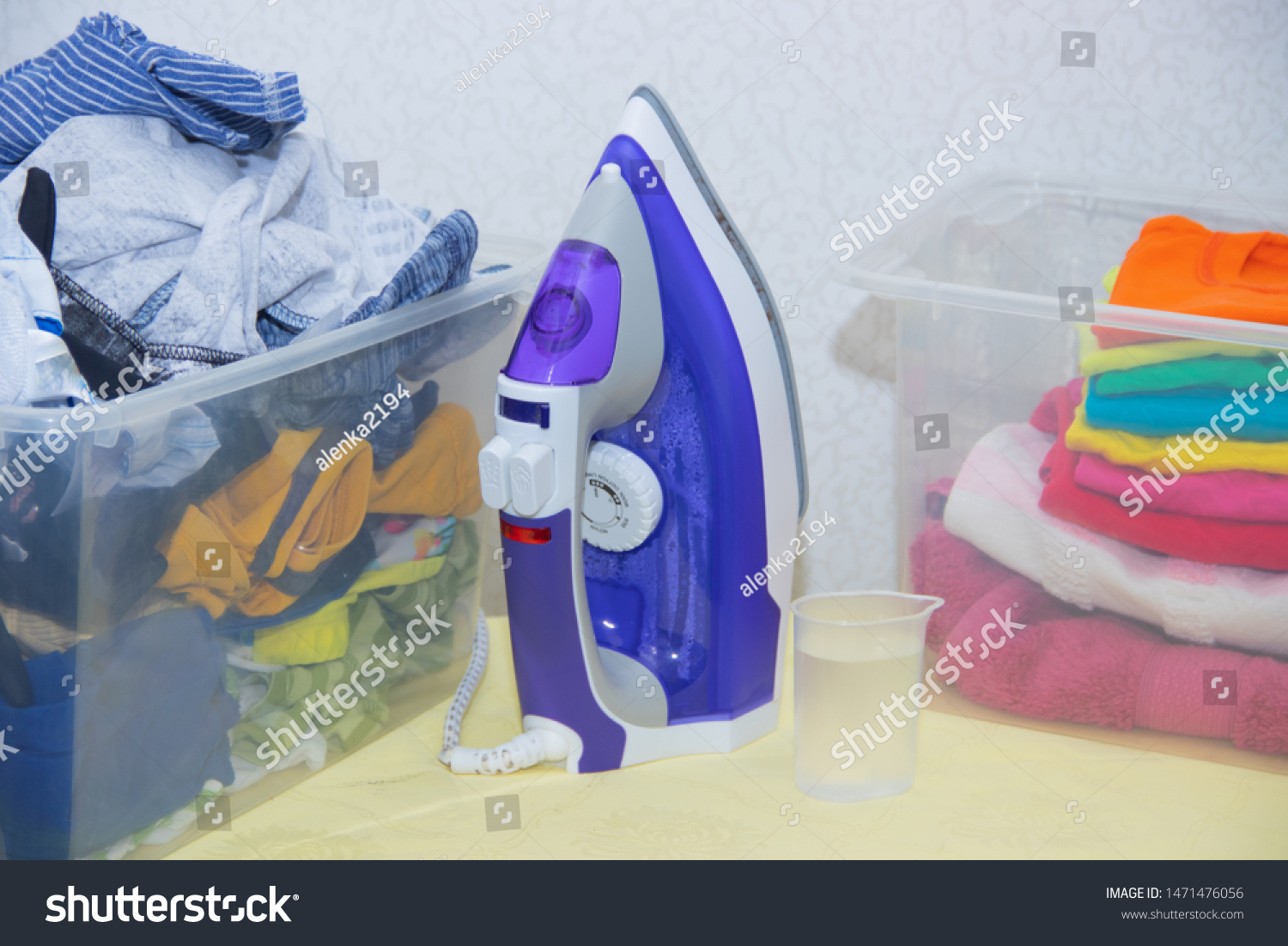 Iron and baby clothes. Colored clothes on an ironing board. Bright t-shirts. Ironed and non-ironed colored children's underwear on the board. Ironing board. A pile of things. #1471476056