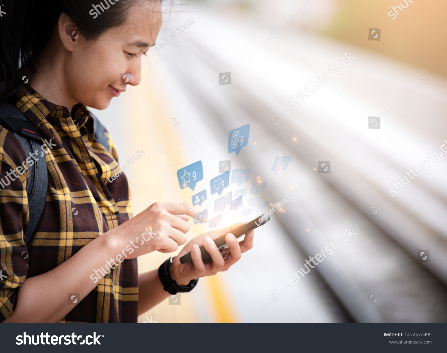 Beautiful asian girl Standing waiting for the train And she is using smartphone To find information on tourism. Travel and tourism concept.social media. #1472572499