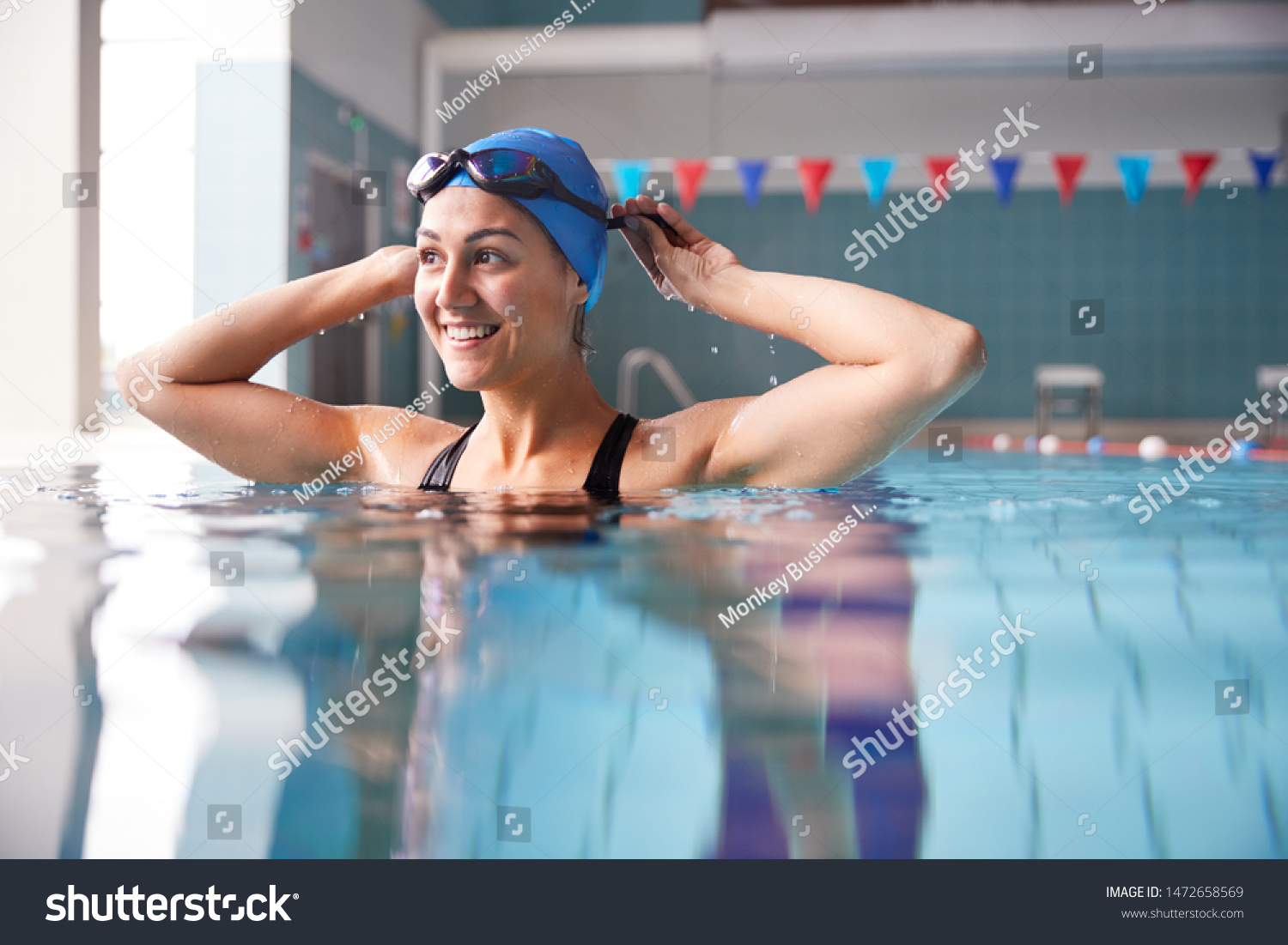 Female Swimmer Wearing Hat And Goggles Training In Swimming Pool #1472658569
