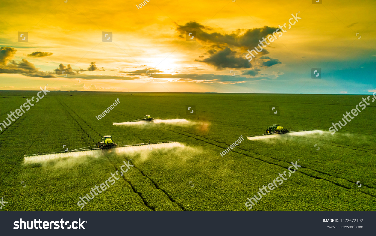 Agricultural sprayers making application at the end of the day with beautiful sunset