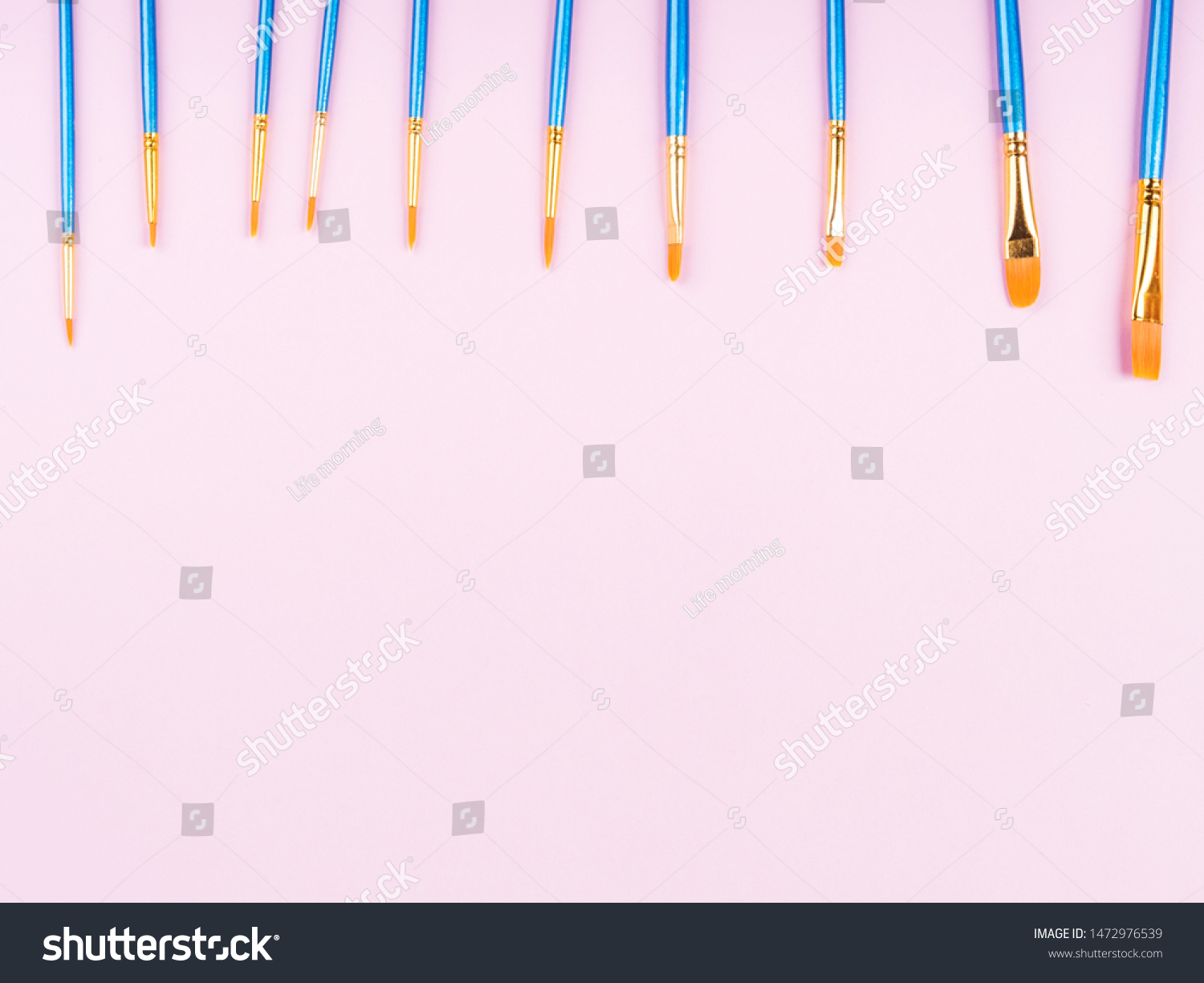 Blue paintbrushes on pink background. Art supply concept #1472976539