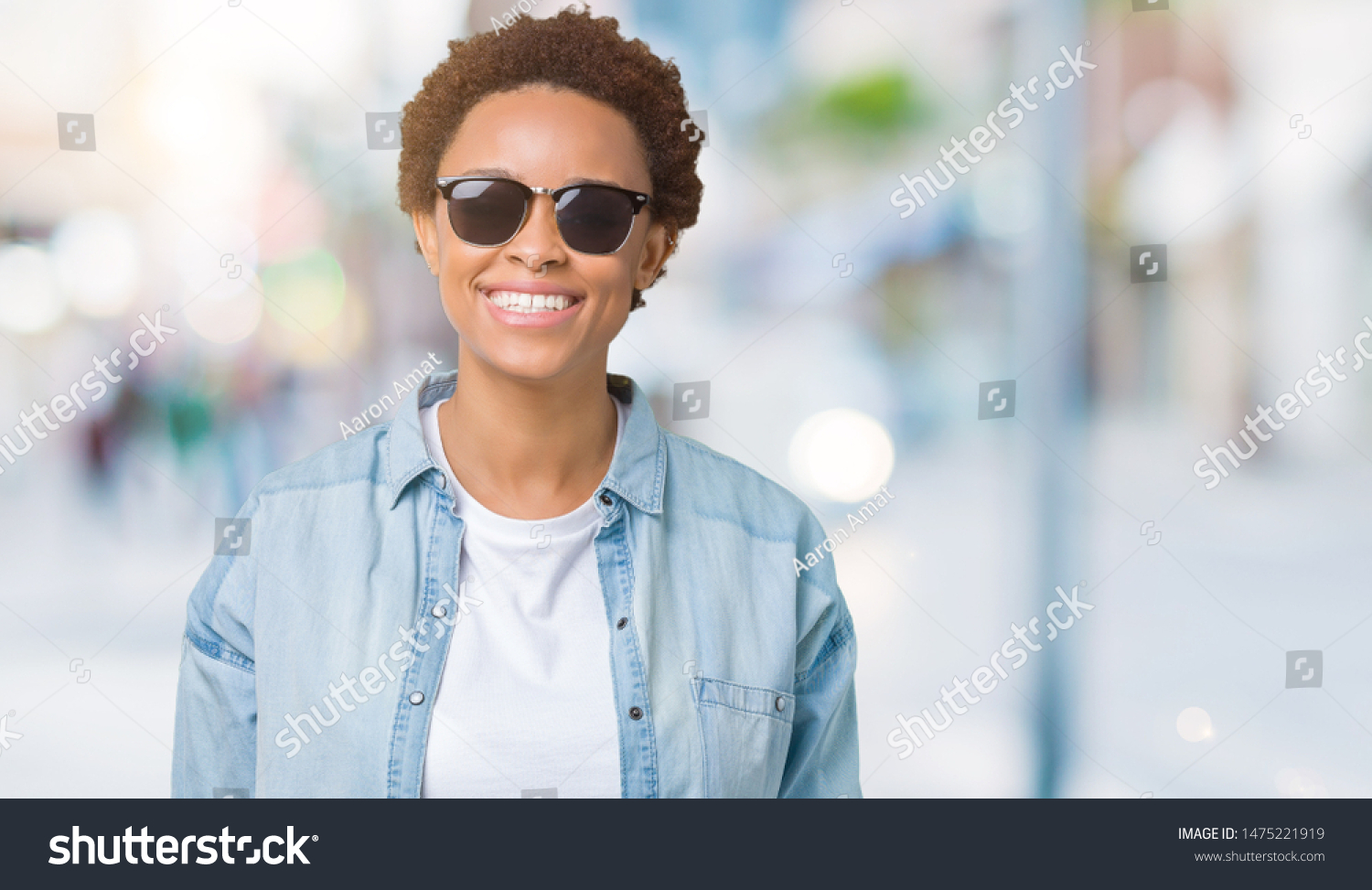 Beautiful young african american woman wearing sunglasses over isolated background with a happy and cool smile on face. Lucky person. #1475221919