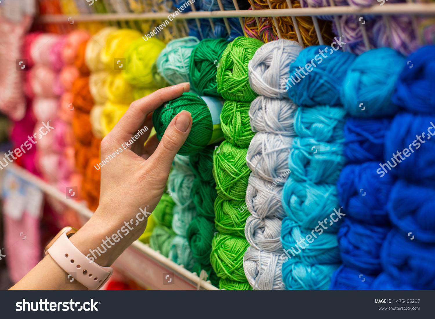 Close Up of yarn balls. Girl hand choosing Yarn in Knitting Shop. knitting shop center. A lot of color yarn for knitting. Selection of colorful yarn wool on shopfront #1475405297