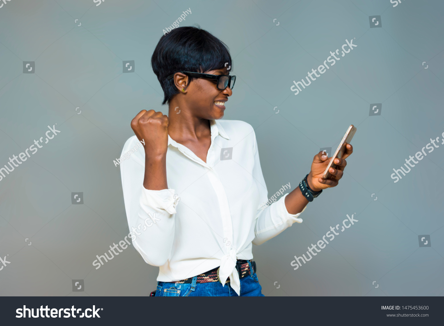 Black skin girl wearing glasses using mobile phone excited after receiving credit alert form her Bank #1475453600