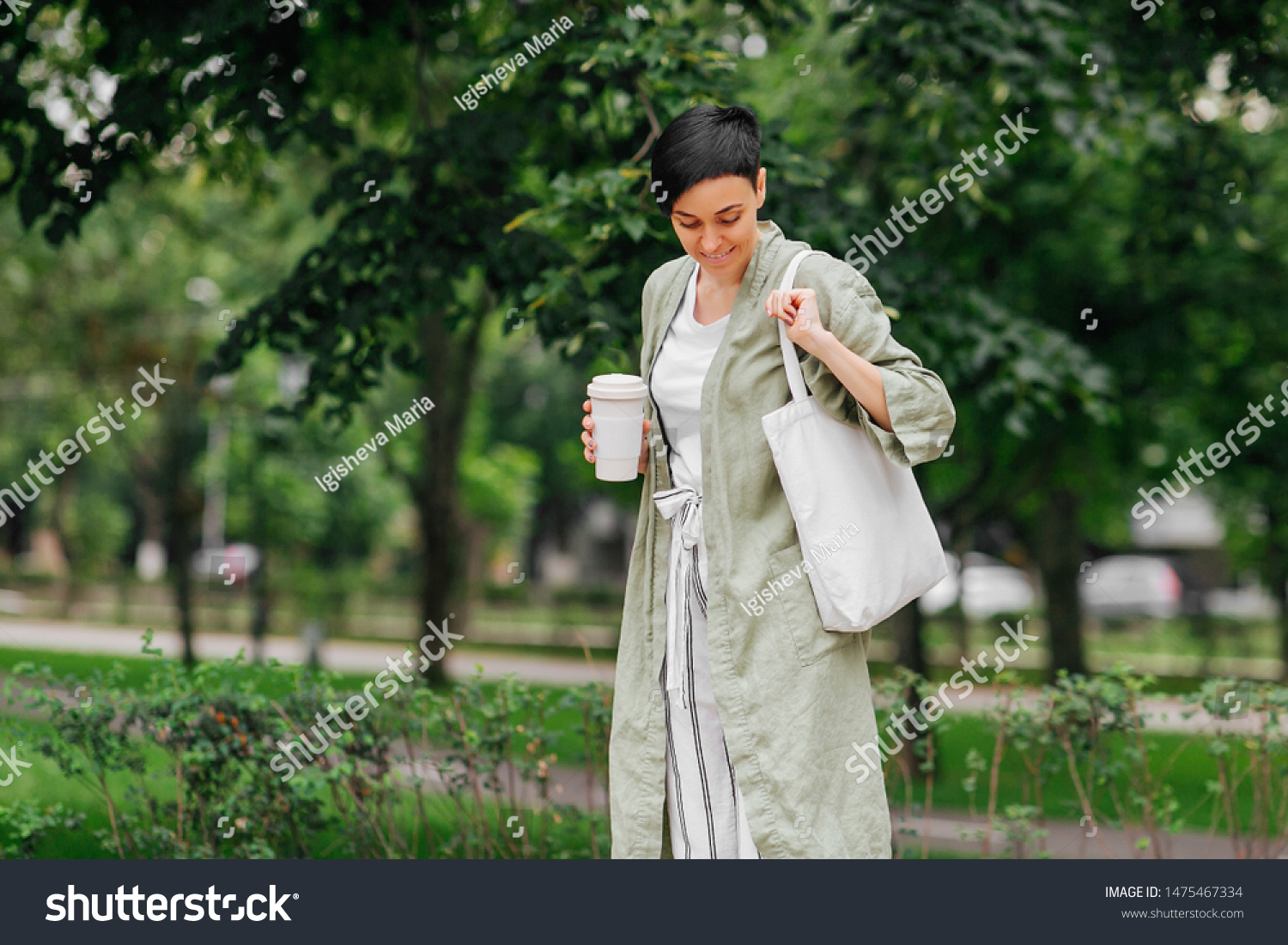 Woman with short hair holding reusable coffee cup and eco bag enjoying morning. Eco friendly concept. #1475467334