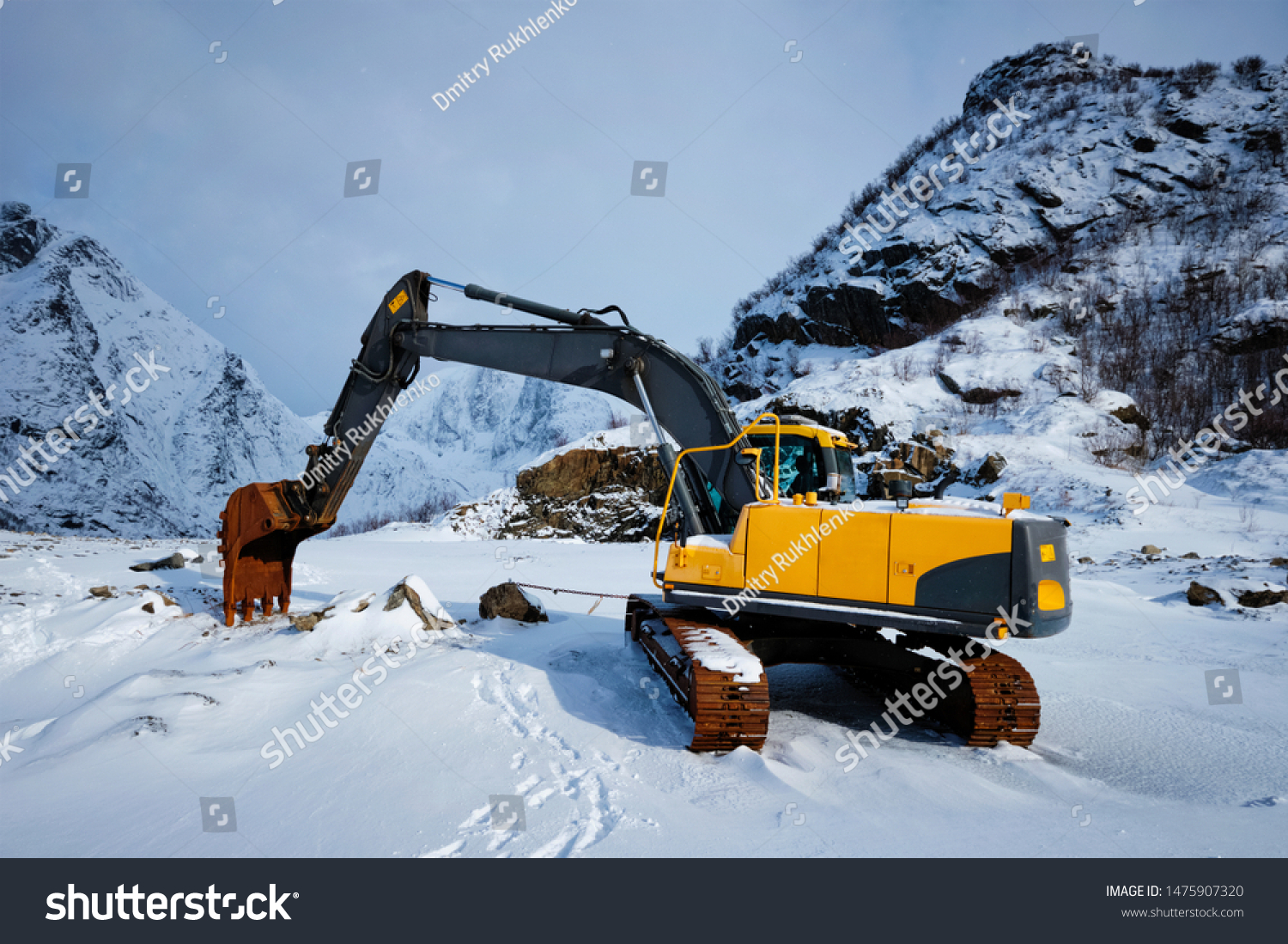 Old excavator with excavator bucket in winter. Road construction in snow. Lofoten islands, Norway #1475907320
