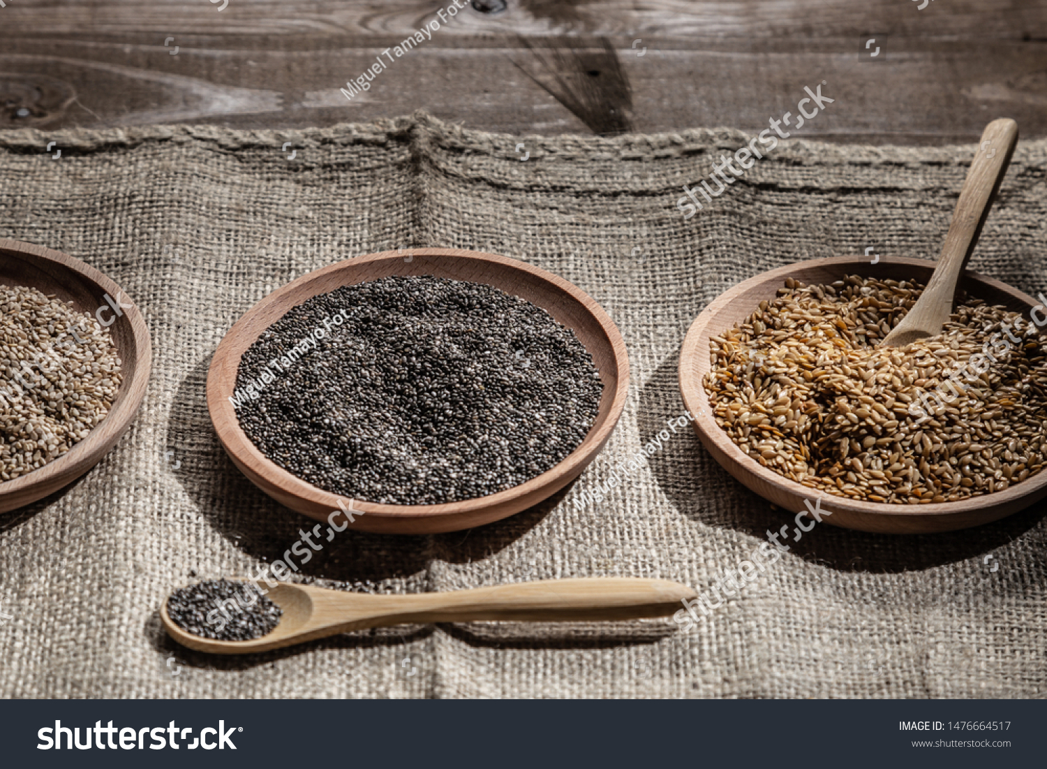 Sesame, chia and flax seeds in wooden dishes, wooden spoon with chia on wooden base.  #1476664517