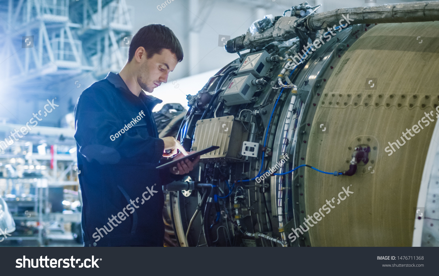 Aircraft Maintenance Mechanic Inspecting and Working on Airplane Jet Engine in Hangar #1476711368