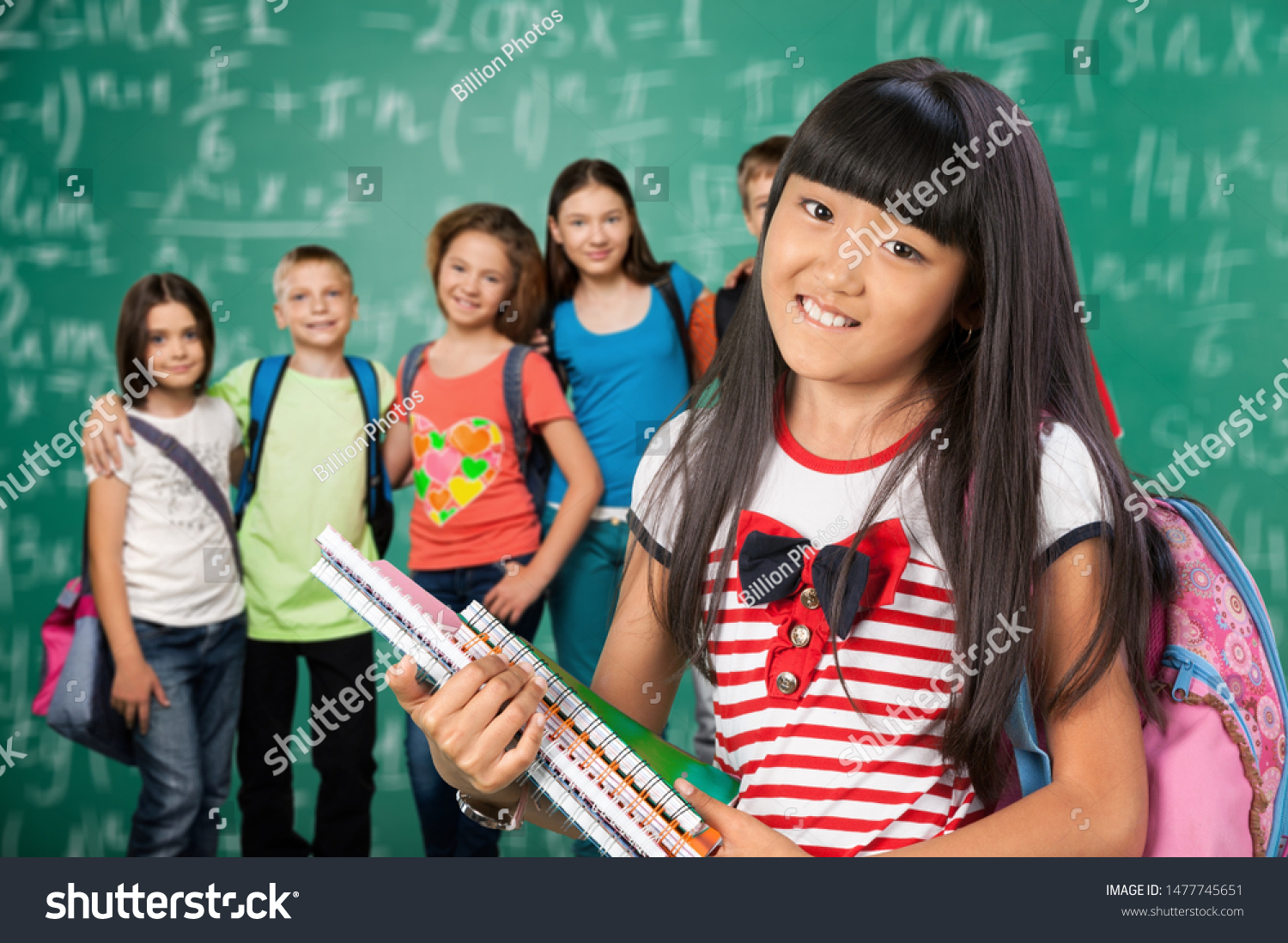 Little schoolgirl and group child on classroom background #1477745651