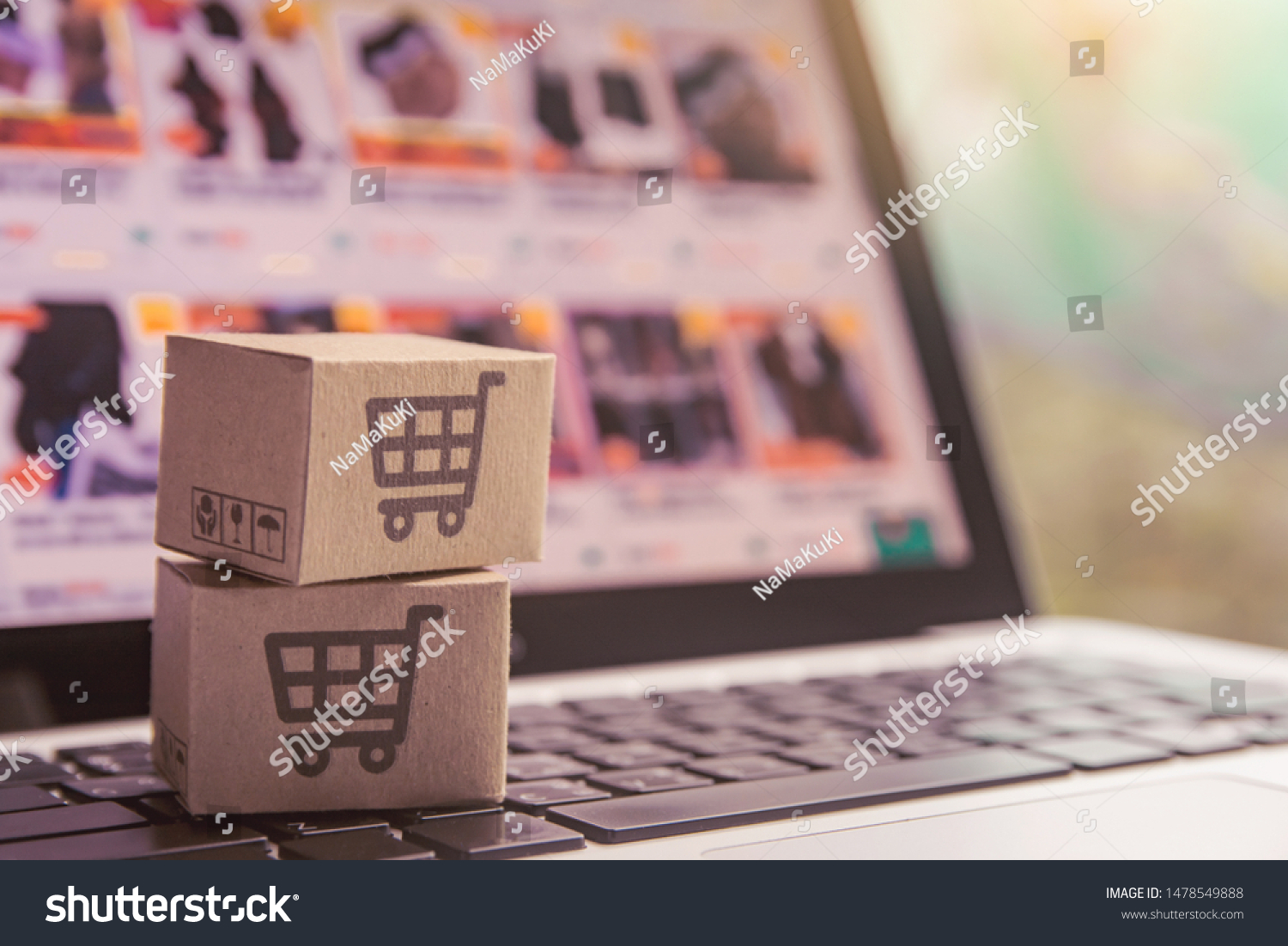 Online shopping - Paper cartons or parcel with a shopping cart logo on a laptop keyboard. Shopping service on The online web and offers home delivery. #1478549888